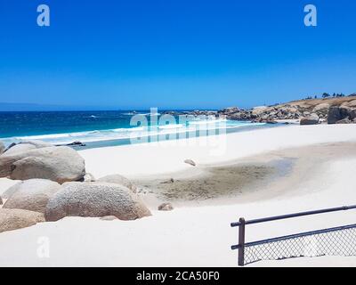 Camps Bay Beach derrière la clôture et les rochers au Cap. Banque D'Images