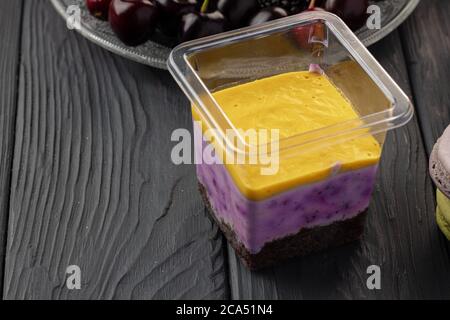 Mousse dessert dans une boîte plastique transparente sur table en bois noir Banque D'Images