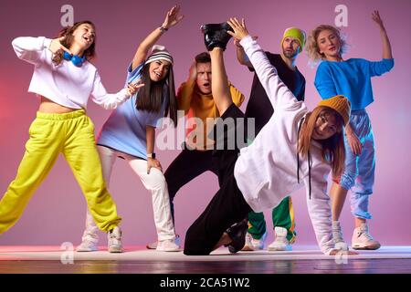 Jeune groupe d'adolescents passant une fête d'anniversaire dans un studio de danse, pratiquant des films de hip hop, sautant gaiement, breakdancing sur le sol, prise de vue en intérieur, m Banque D'Images