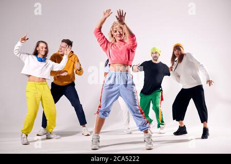 Joyeux groupe actif d'amis dansant ensemble sur la piste de danse, vêtu décontracté de vêtements colorés, ayant du temps libre, passant du temps gaieté Banque D'Images