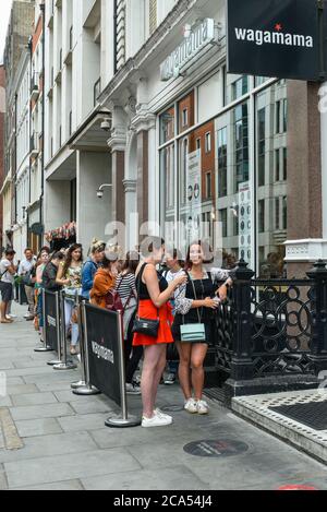 Londres, Royaume-Uni. 4 août 2020. Les gens font la queue devant un restaurant Wagamama près de Carnaby Street. La chaîne de restaurants participe au programme « manger dehors pour aider » du gouvernement britannique. Les clients peuvent bénéficier d'une réduction de 50 % (jusqu'à 10 £) sur la nourriture ou les boissons non alcoolisées à consommer, tous les lundis, mardis et mercredis entre le 3 et le 31 août. Le programme vise à accroître les revenus de l'industrie hôtelière qui a été durement touchée pendant la pandémie du coronavirus. Credit: Stephen Chung / Alamy Live News Banque D'Images