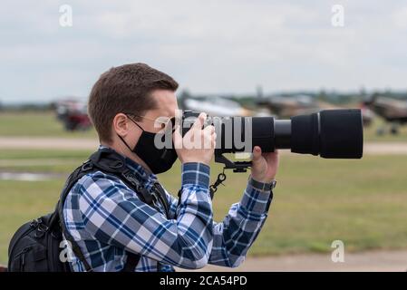 Imperial War Museum Duxford, Cambridgeshire, Royaume-Uni. 4 août 2020. Après une longue période de fermeture due à l'enfermement du coronavirus COVID-19, le musée a rouvert ses portes aux visiteurs le 1er août. Aujourd'hui, le musée a tenu son premier événement d'exposition aérienne, intitulé a Showcase Day. Il s'agissait d'un événement réservé à l'avance avec une limite de visiteurs considérablement réduite, et le public en visite devait se conformer à des directives strictes lors de l'entrée dans les expositions intérieures. Un photographe avec un objectif zoom long et un masque facial Banque D'Images