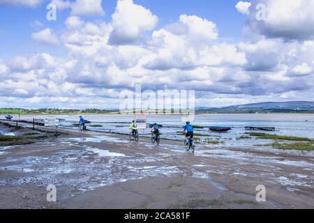 Le cyciste traverse la route de la chaussée à Sunderland point, est un petit village parmi les marais, sur une péninsule balayée par le vent entre l'embouchure de la rivière lu Banque D'Images