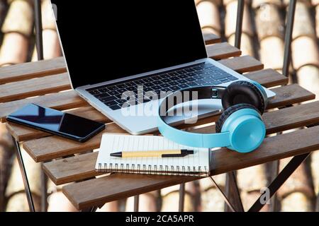 Image isolée d'une table de terrasse avec casque portable et bloc-notes. Je travaille de la terrasse à la maison Banque D'Images