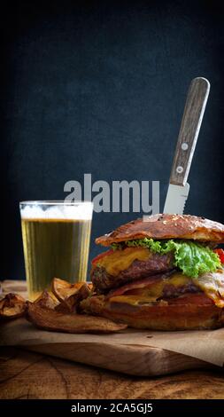 Vue de délicieux hamburgers et frites avec un verre de bière sur une table en bois Banque D'Images