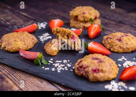 Biscuits faits maison aux fraises et flocons d'avoine sur ardoise noire Banque D'Images