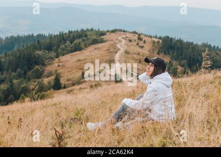 Femme assise sur le sol à la recherche des montagnes au concept de randonnée Banque D'Images