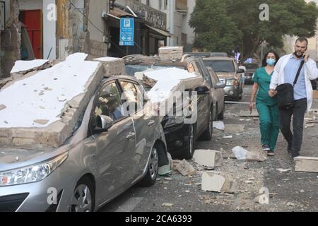 Beyrouth, Liban. 4 août 2020. Des gens marchent à côté de véhicules endommagés après l'explosion à Beyrouth, Liban, le 4 août 2020. Les deux énormes explosions qui ont secoué la capitale libanaise Beyrouth mardi ont fait des dizaines de morts et de blessés, a rapporté la chaîne de télévision al-Jadeed. Credit: Bilal Jawich/Xinhua/Alay Live News Banque D'Images