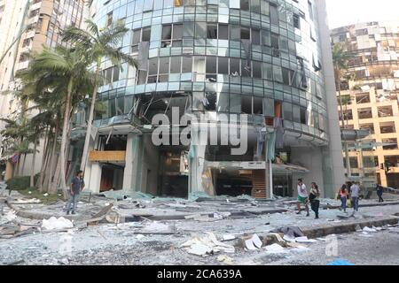 Beyrouth, Liban. 4 août 2020. Les gens marchent devant un bâtiment détruit après l'explosion à Beyrouth, Liban, le 4 août 2020. Les deux énormes explosions qui ont secoué la capitale libanaise Beyrouth mardi ont fait des dizaines de morts et de blessés, a rapporté la chaîne de télévision al-Jadeed. Credit: Bilal Jawich/Xinhua/Alay Live News Banque D'Images