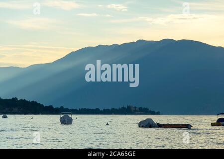 Vue sur le lac de Garde en début de matinée ou en soirée. L'eau est calme, le ciel est partiellement nuageux. Les petits bateaux dansent sur l'eau. L'humeur est rêveuse. Banque D'Images