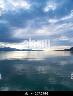 Vue sur le lac de Garde en début de matinée ou en soirée. L'eau est calme, le ciel est partiellement nuageux. Les petits bateaux dansent sur l'eau. L'humeur est rêveuse. Banque D'Images