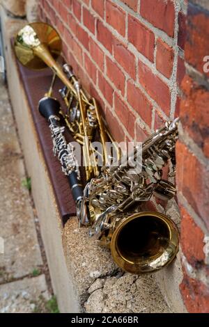 Instruments de musique dont clarinette trompette trombone et saxophone sur mur de briques à l'extérieur du club de jazz Banque D'Images