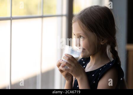 Bonne petite fille regarder dans fenêtre boire du lait Banque D'Images