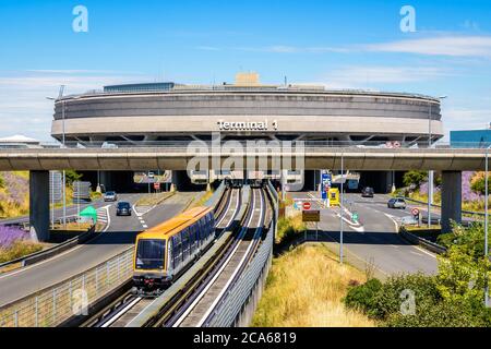 Une navette de l'aéroport CDGVAL quitte le bâtiment circulaire en béton du terminal 1 de l'aéroport Paris-Charles de Gaulle par une journée ensoleillée. Banque D'Images