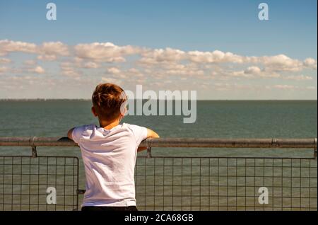 Garçon qui regarde la mer de derrière Banque D'Images