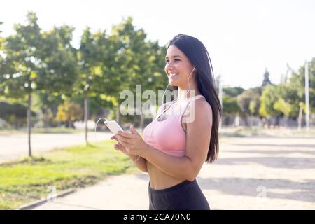 Une jeune femme à la course met de la musique sur son téléphone portable avant de faire de l'exercice Banque D'Images