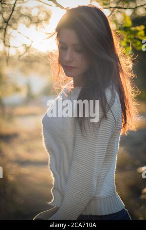 Jolie fille avec de longs cheveux bruns dans un contre-jour à coucher de soleil Banque D'Images