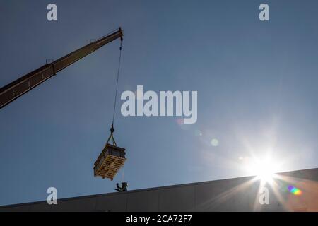 Denver, Colorado - les panneaux solaires et autres équipements pour une installation d'énergie solaire sont soulevés au sommet d'un nouveau bâtiment de logement abordable. Le SO Banque D'Images