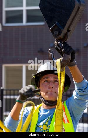 Denver, Colorado - les panneaux solaires et autres équipements pour une installation d'énergie solaire sont soulevés au sommet d'un nouveau bâtiment de logement abordable. Le SO Banque D'Images