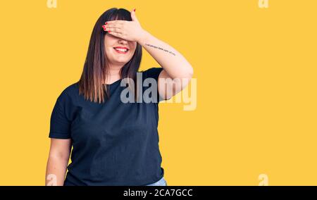 Jeune femme de taille plus portant des vêtements décontractés souriant et riant avec la main sur le visage couvrant les yeux pour la surprise. Concept aveugle. Banque D'Images