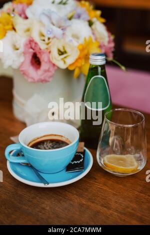 Café dans une tasse bleue, eau acide et boîte de fleurs sur la table dans le café Banque D'Images