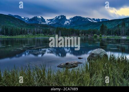 Coucher de soleil sur le lac Sprague dans les montagnes rocheuses du colorado. Les gens pêchent à l'ombre de la magnifique chaîne de montagnes Banque D'Images