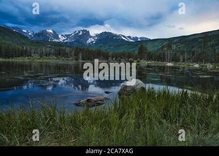 Coucher de soleil sur le lac Sprague dans les montagnes rocheuses du colorado. Les gens pêchent à l'ombre de la magnifique chaîne de montagnes Banque D'Images