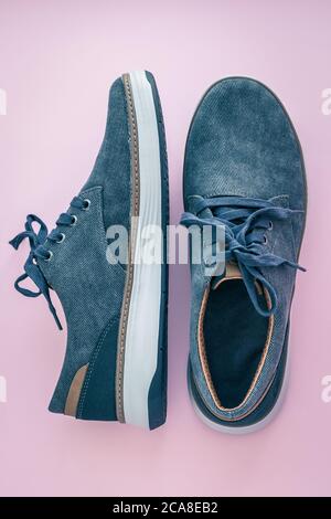 Une paire de sneakers pour homme. Chaussures en denim bleu sur fond rose. Chaussures en tissu confortables. Vue de dessus. Concept de mode décontracté Banque D'Images