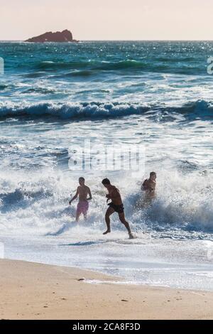 Hommes vacanciers s'amuser en mer à Fistral Beach à Newquay en Cornouailles. Banque D'Images
