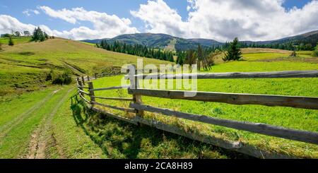 clôture sur la colline en zone rurale. paysage du début de l'automne dans les montagnes carpathes. temps ensoleillé avec nuages sur le ciel. collines roulant dans tho le lointain Banque D'Images
