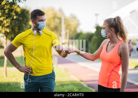 Le jeune couple se prépare à faire de l'exercice en plein air avec des masques protecteurs. Covid-19 comportement responsable. Banque D'Images