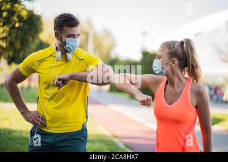 Le jeune couple se prépare à faire de l'exercice en plein air avec des masques protecteurs. Covid-19 comportement responsable. Banque D'Images