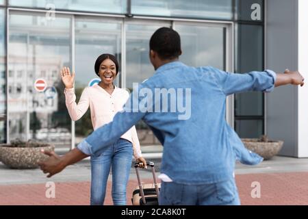 Bonne fille africaine à la rencontre de son petit ami après l'atterrissage à l'aéroport, en agitant la main Banque D'Images