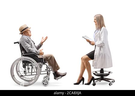 Prise de vue en profil d'une jeune femme médecin assise sur une chaise et parlant à un homme âgé dans un fauteuil roulant isolé sur un backgrou blanc Banque D'Images