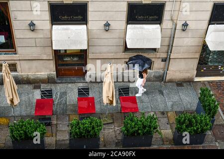 Vue panoramique d'une jeune fille marchant avec un parasol sur le trottoir d'un restaurant fermé en journée de pluie, Turin, Piémont, Italie Banque D'Images