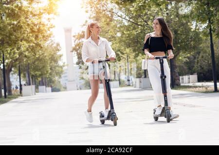 Deux amies qui font du scooter électrique dans le parc Banque D'Images
