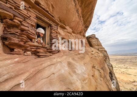 Prêtre regardant dehors, une petite fenêtre sculptée dans des rochers dans l'église Abuna Yemata Guh, montagnes Gheralta, région du Tigré, Ethiopie, Afrique Banque D'Images