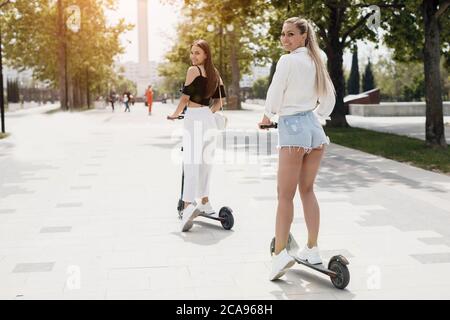 Deux amies qui font du scooter électrique dans le parc Banque D'Images