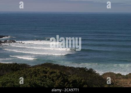 Côte avec rochers, ciel bleu et vagues en été Banque D'Images