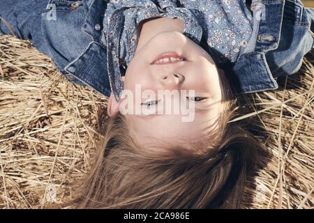 Portrait d'une petite fille à l'envers sur une botte de foin. Photo de haute qualité Banque D'Images