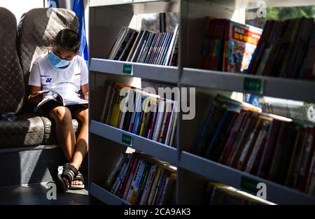 Changchun, province chinoise de Jilin. 5 août 2020. Un garçon lit un livre dans une bibliothèque mobile transformée à partir d'un autobus à Changchun, dans la province de Jilin, dans le nord-est de la Chine, le 5 août 2020. La bibliothèque Changchun a converti un autobus en une bibliothèque mobile qui circule à 15 points de service fixes pour fournir aux citoyens un service de prêt de livres. Credit: Xu Chang/Xinhua/Alay Live News Banque D'Images