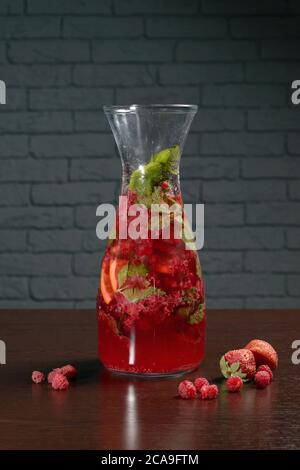 Carafe en verre avec cocktail de baies rouges sur une table en bois avec framboises et fraises. Photos pour les menus du restaurant, du café et du bar Banque D'Images