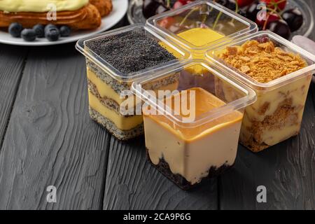 Mousse dessert dans une boîte plastique transparente sur table en bois noir Banque D'Images