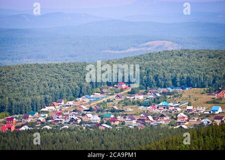 Vue sur le village et les forêts de pins depuis la crête de Chashkovsky. Montagnes de l'Oural. Concept d'éco-tourisme et de randonnée. Banque D'Images