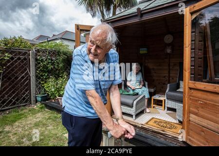 Couple de personnes âgées dans leurs années 80 appréciant le temps chaud d'été dans leur jardin d'été maison, Angleterre, Royaume-Uni Banque D'Images