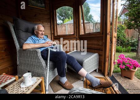 Couple de personnes âgées dans leurs années 80 appréciant le temps chaud d'été dans leur jardin d'été maison, Angleterre, Royaume-Uni Banque D'Images