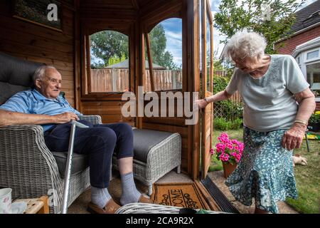 Couple de personnes âgées dans leurs années 80 appréciant le temps chaud d'été dans leur jardin d'été maison, Angleterre, Royaume-Uni Banque D'Images