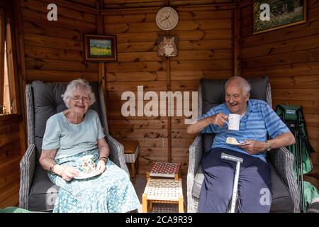 Couple de personnes âgées dans leurs années 80 appréciant le temps chaud d'été dans leur jardin d'été maison, Angleterre, Royaume-Uni Banque D'Images