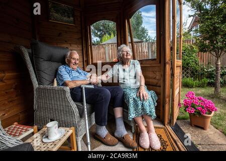 Couple de personnes âgées dans leurs années 80 appréciant le temps chaud d'été dans leur jardin d'été maison, Angleterre, Royaume-Uni Banque D'Images