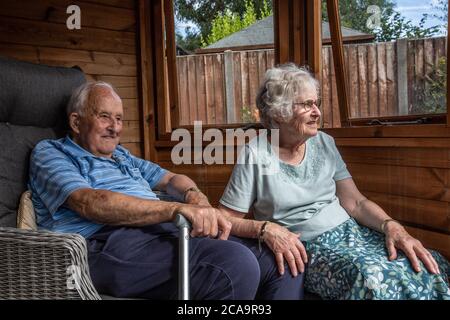 Couple de personnes âgées dans leurs années 80 appréciant le temps chaud d'été dans leur jardin d'été maison, Angleterre, Royaume-Uni Banque D'Images